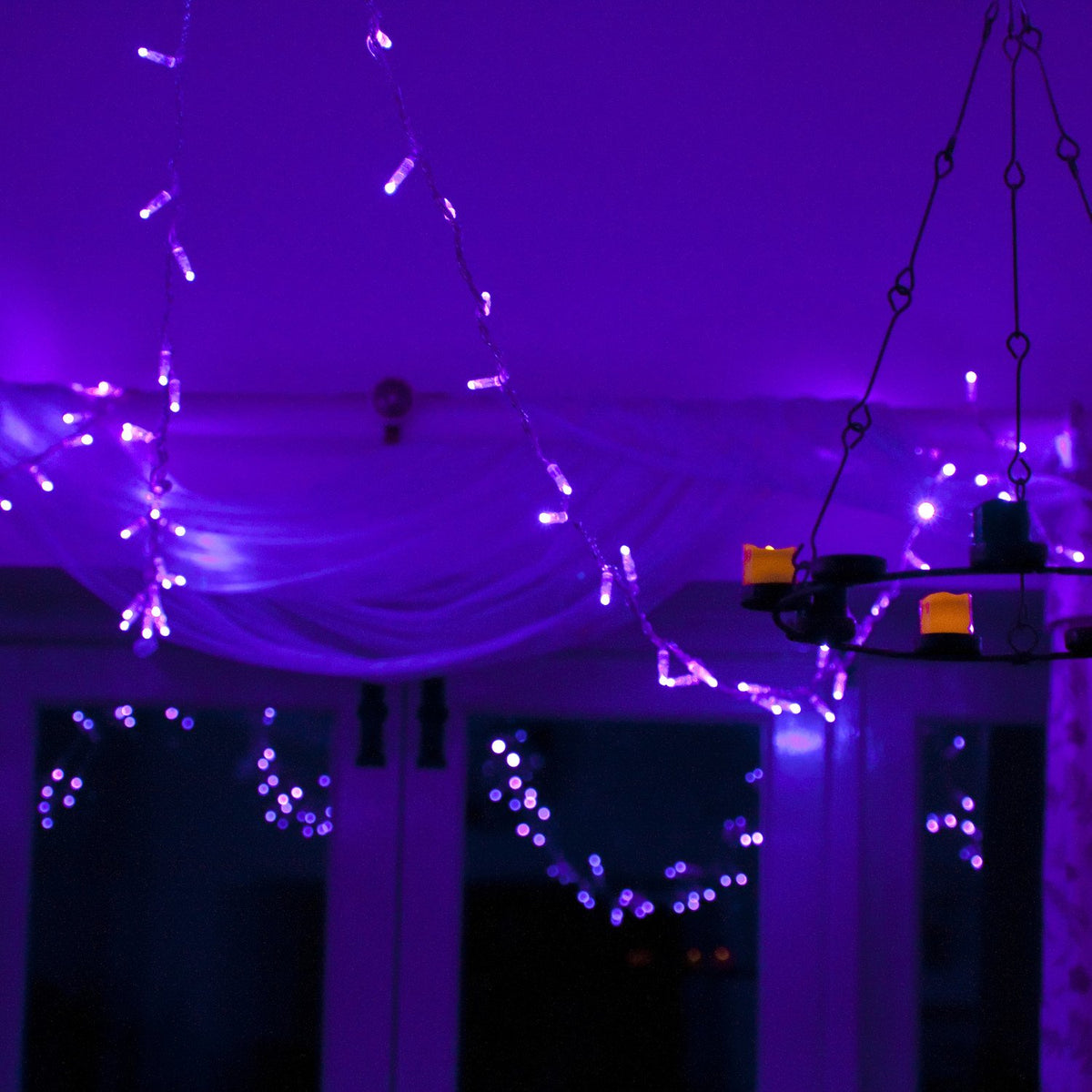 Lila leuchtende LED-Lichterkette mit transparentem Kabel in einem dunklen Raum dekorativ aufgehängt