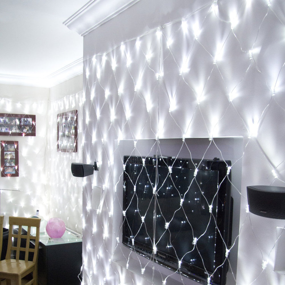Weißes LED-Lichternetz hängt beleuchtet an Wohnzimmerwand mit Fernseher und Lautsprechern