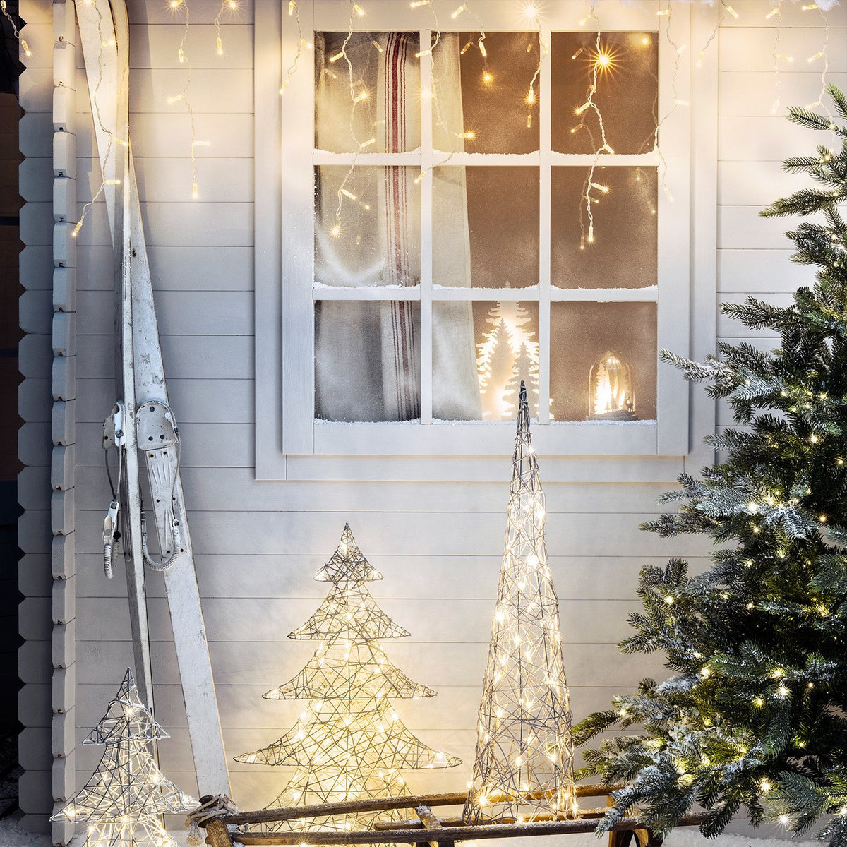 Winterliche Dekoration mit Eiszapfen Lichterkette, Schnee und beleuchteten Deko-Bäumen