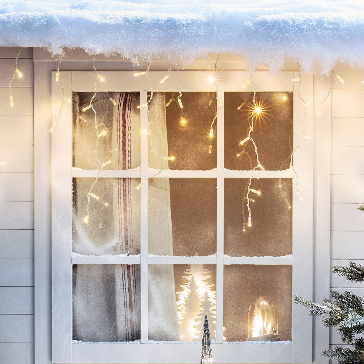 Fenster mit Schnee und warmweißer Eiszapfen Lichterkette dekoriert