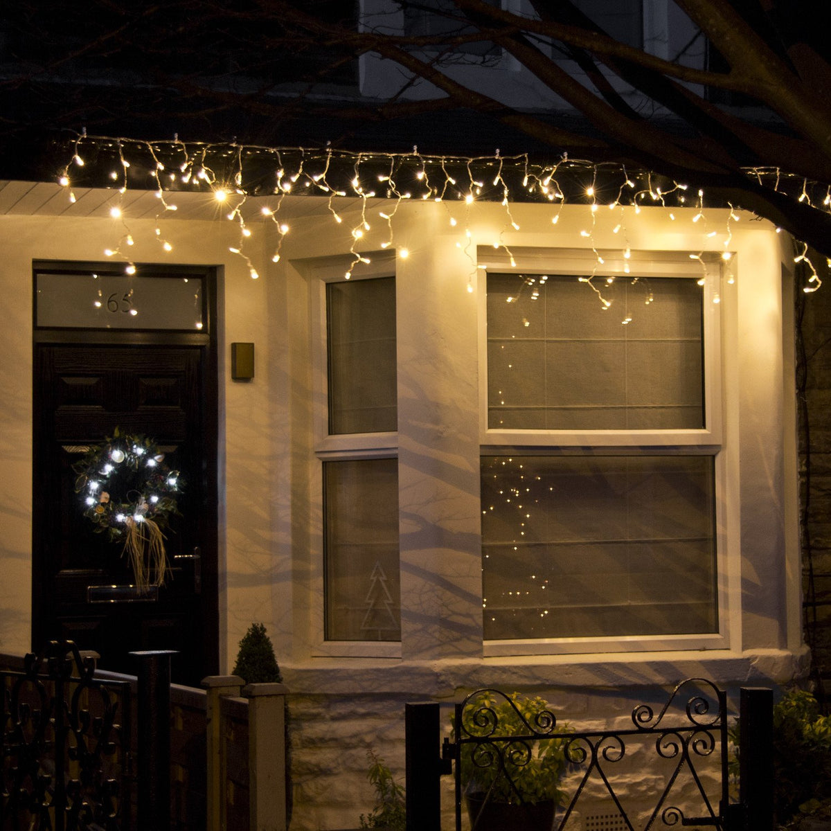 Hausfront mit warmweißer Eiszapfen Lichterkette an der Dachrinne