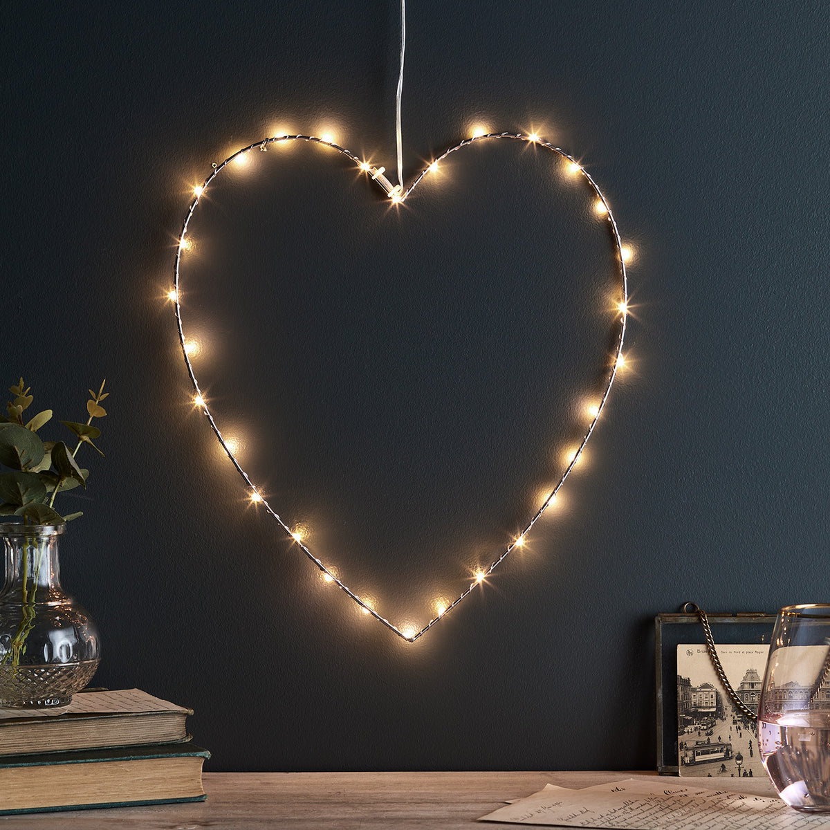 Roségoldenes Herz aus Metall mit 30 warmweißen Micro LEDs an dunkler Wand beleuchtet