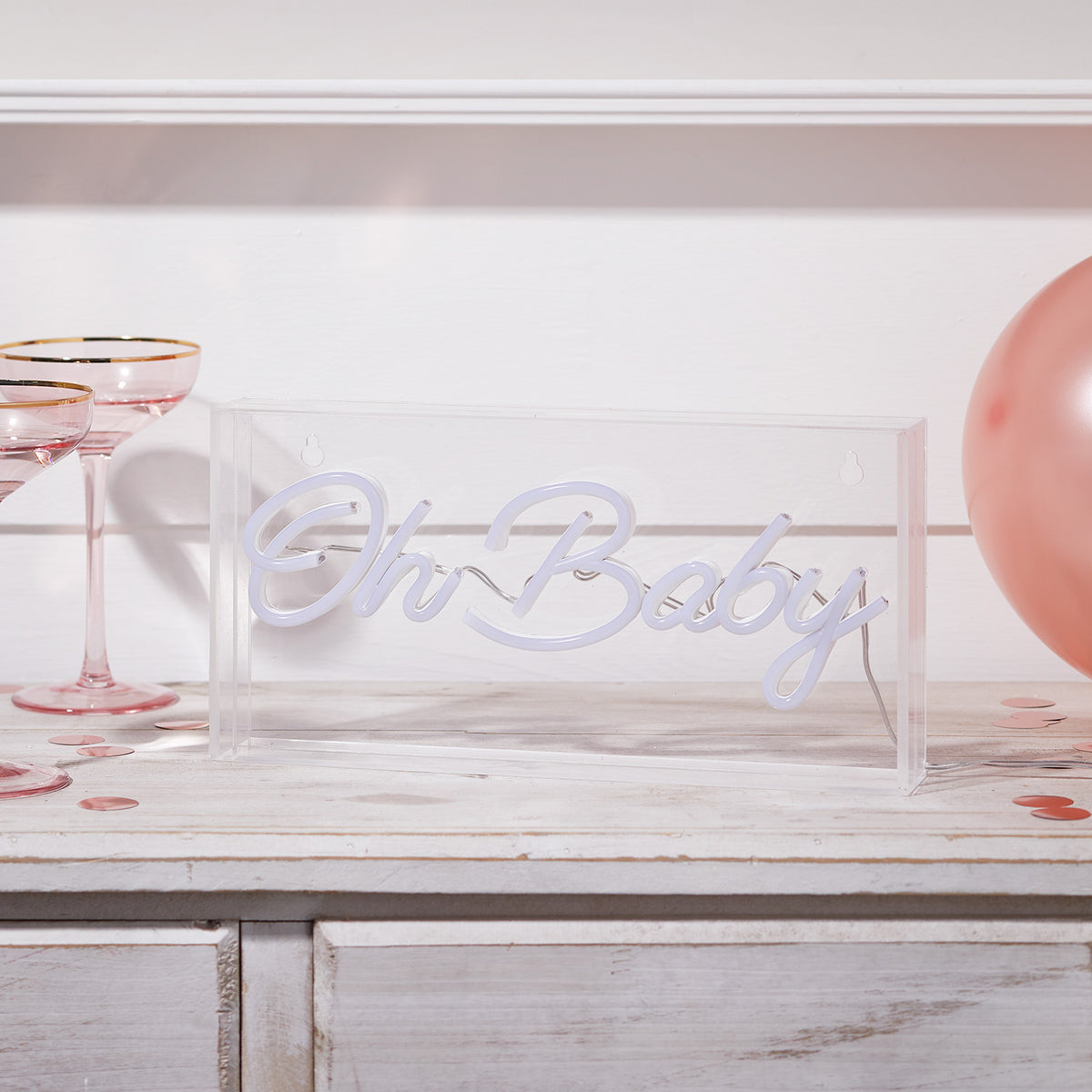 Neon Schriftzug Oh Baby in transparenter Acrylbox ohne Beleuchtung auf Holzfläche