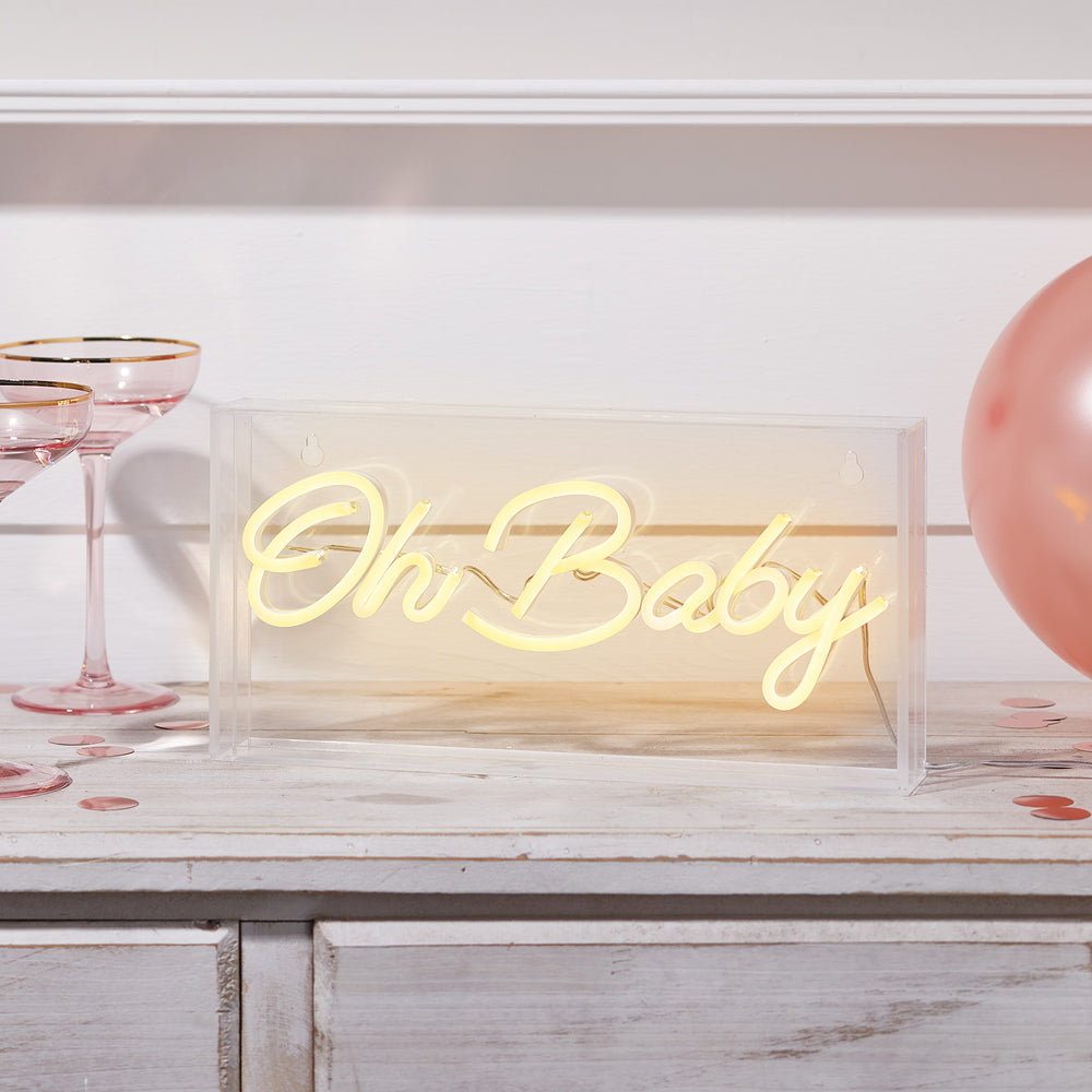 Leuchtender Neon Schriftzug Oh Baby in warmweiß in transparenter Acrylbox auf Holzfläche