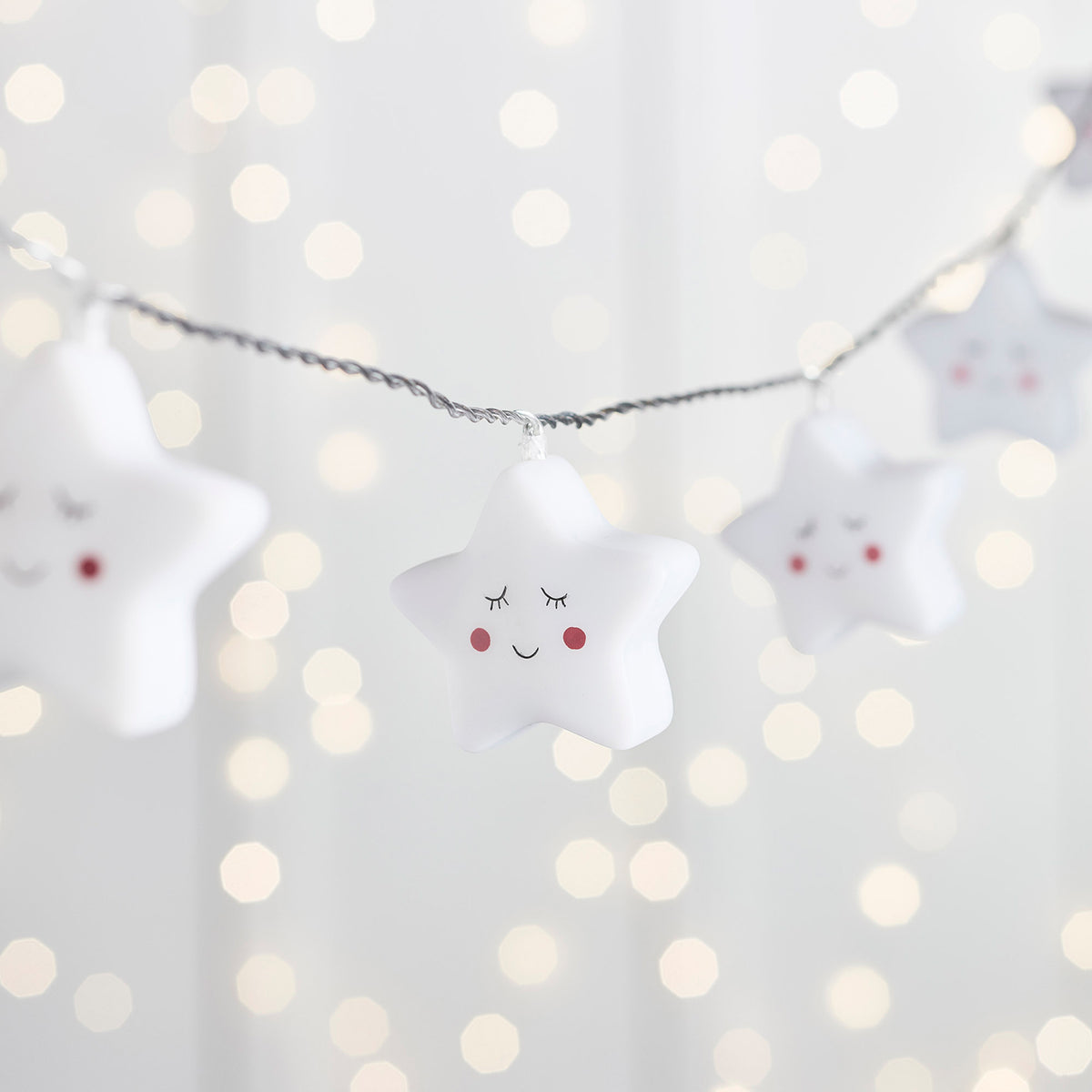 Sternförmige LED-Lichterkette mit lächelnden Gesichtern und rosa Wangen im Kinderzimmer