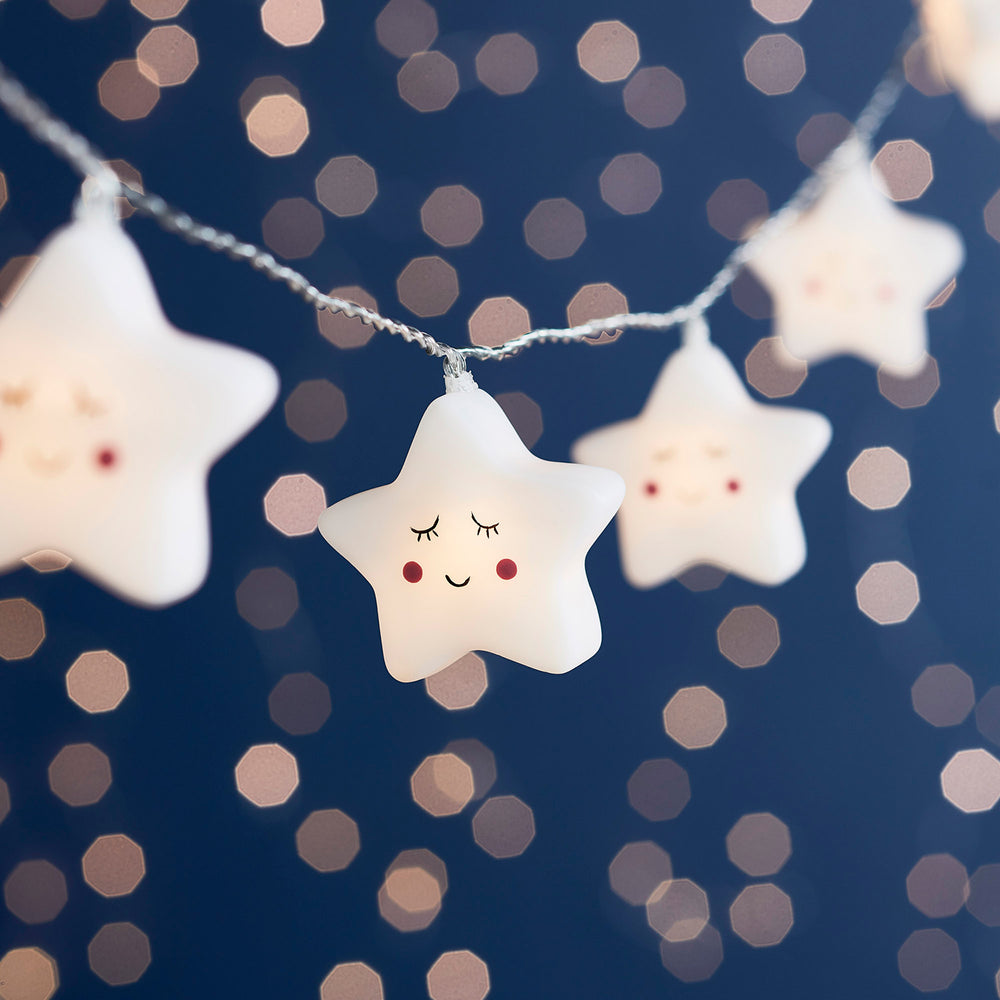 LED Lichterkette mit weißen Sternen und lächelnden Gesichtern vor dunklem Hintergrund
