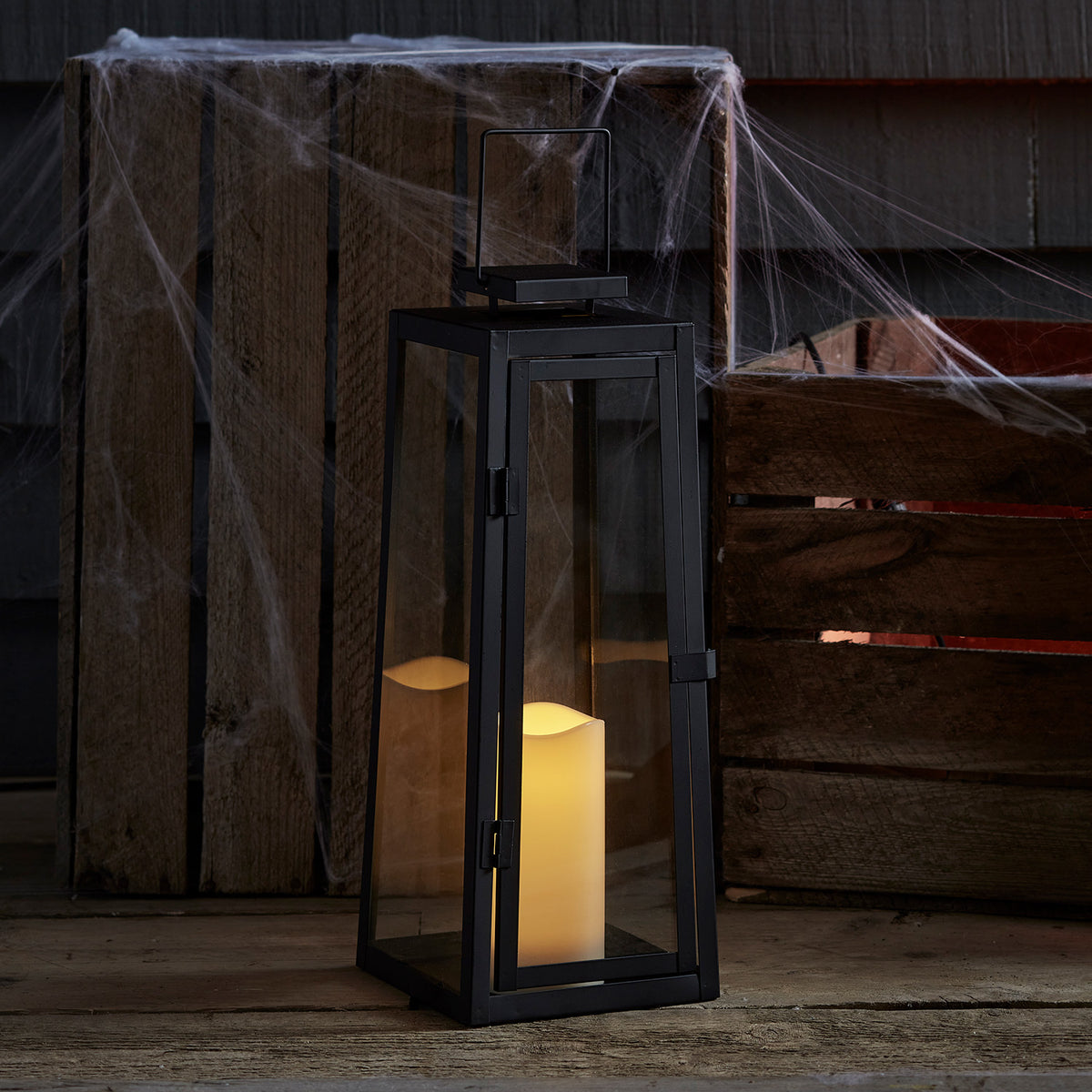 Solar Laterne mit LED Kerze auf Holz neben Holzkiste und Spinnweben dekoriert