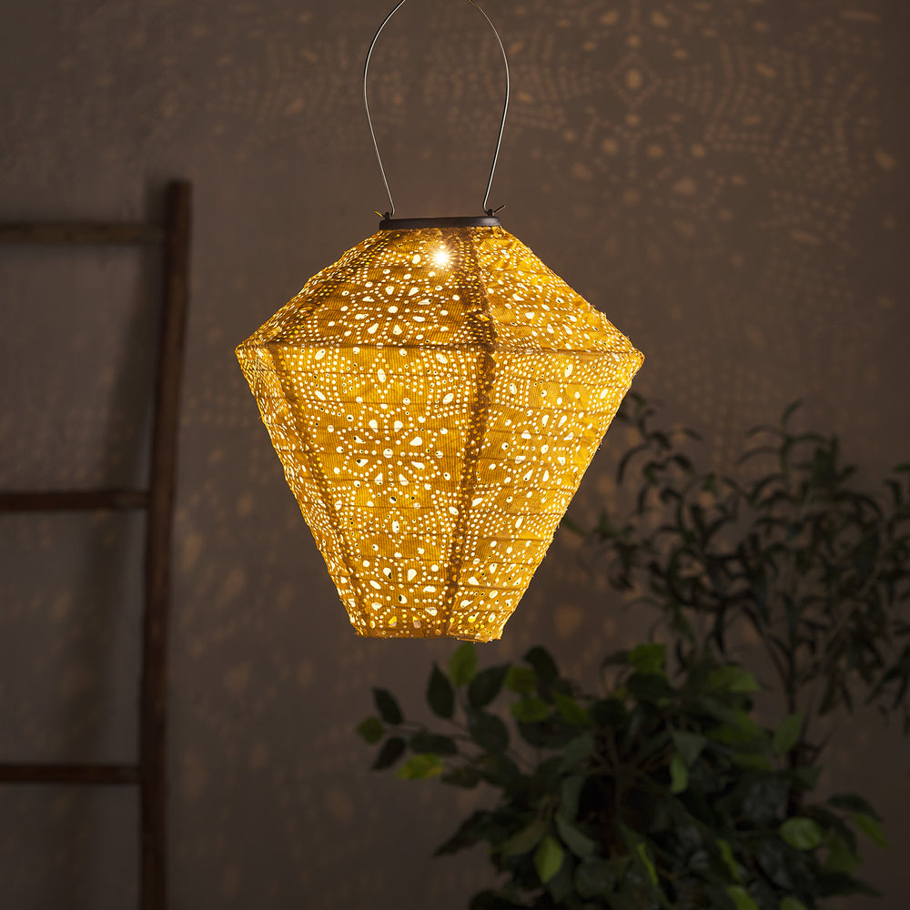 Gelber Tyvek Solar Lampion mit Muster leuchtet und wirft Lichtmuster an Wand