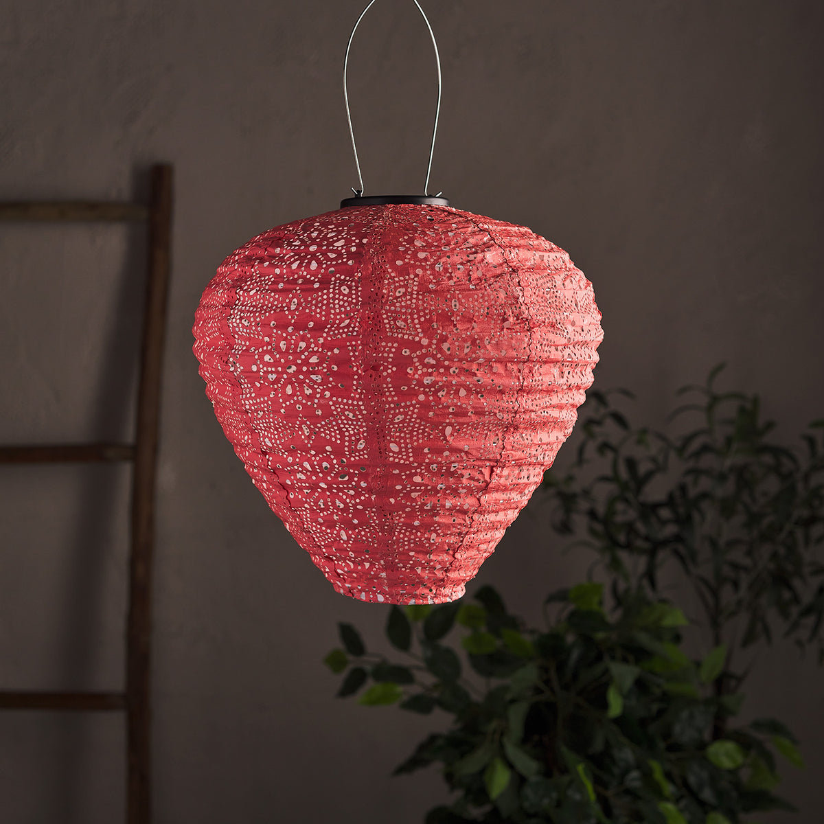 Unbeleuchteter pinkfarbener Solar-Lampion aus Tyvek mit Cut-Out-Muster vor dunklem Hintergrund