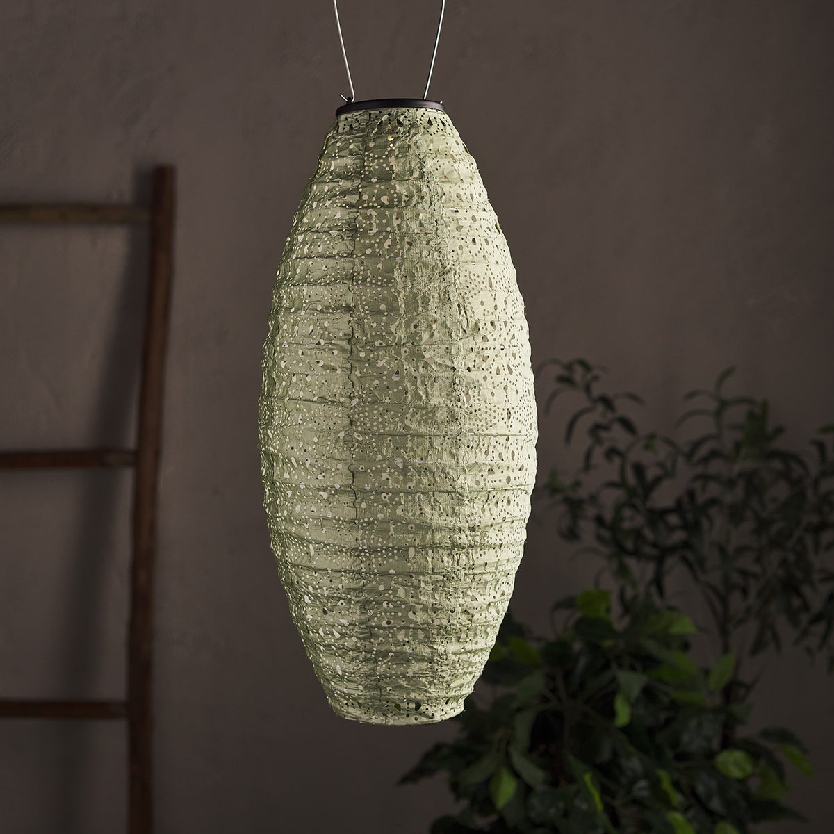 Unbeleuchteter ovaler Tyvek Solar Lampion in mintgrün mit Lochmuster vor dunklem Hintergrund