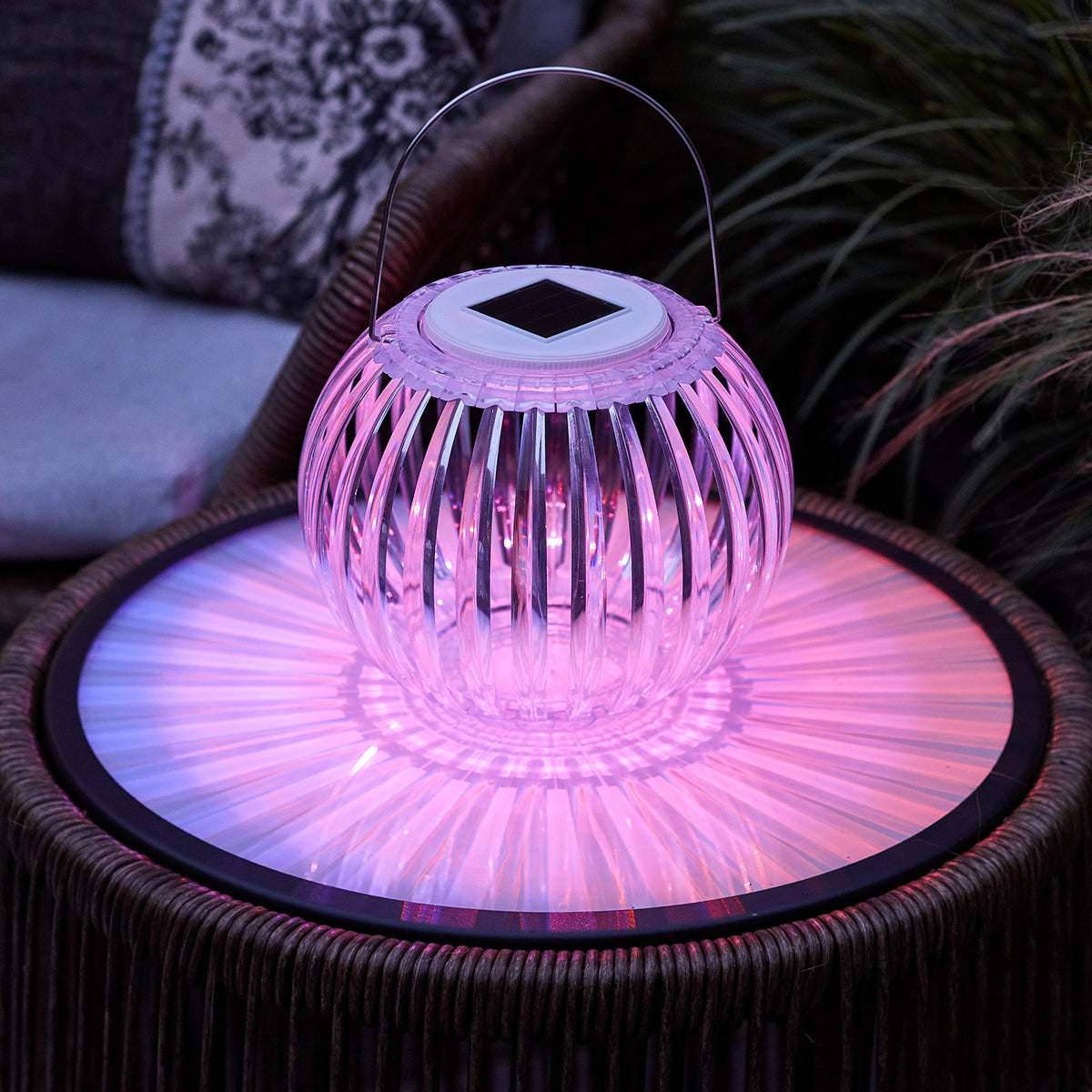 Solar Hängeleuchte mit violettem Licht auf Gartentisch, transparente Acryllampe mit Henkel
