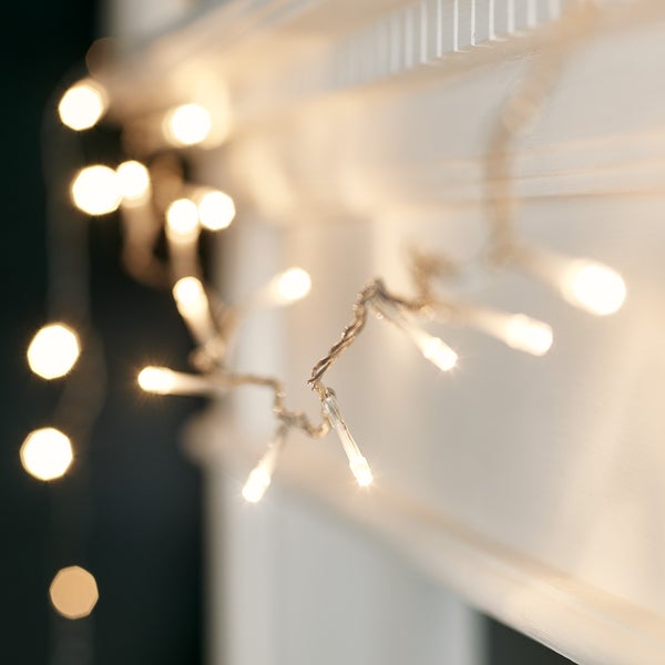 Nahaufnahme der warmweißen LED Lichterkette mit transparentem Kabel an weißer Wand