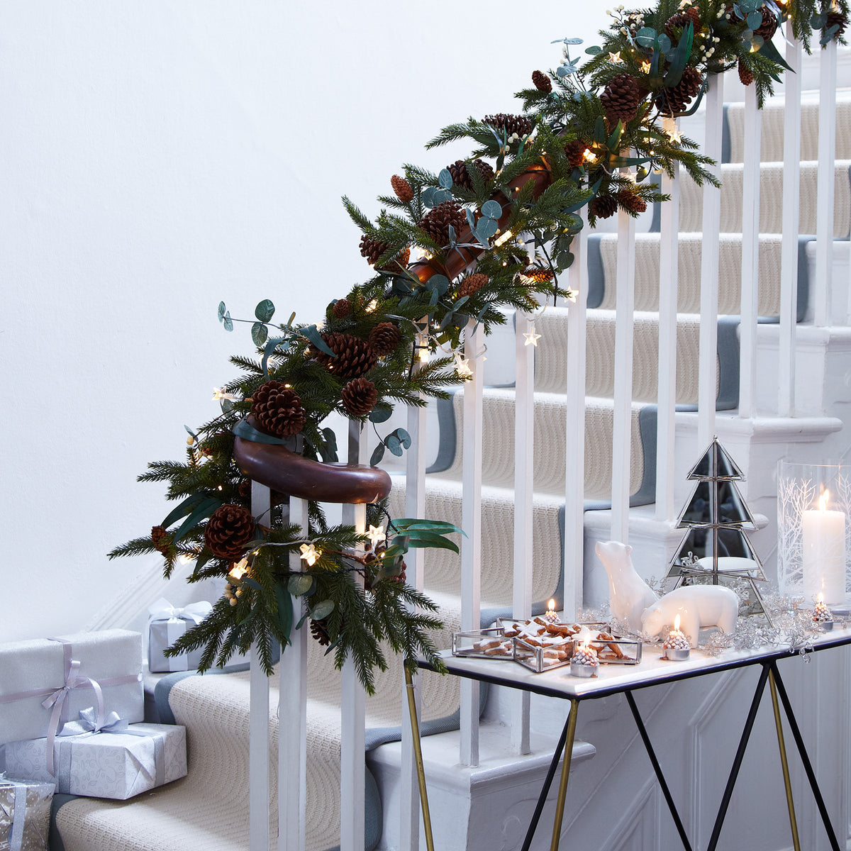 Weihnachtliche Treppendekoration mit Tannengrün, Zapfen und warmweißer Sternen-Lichterkette