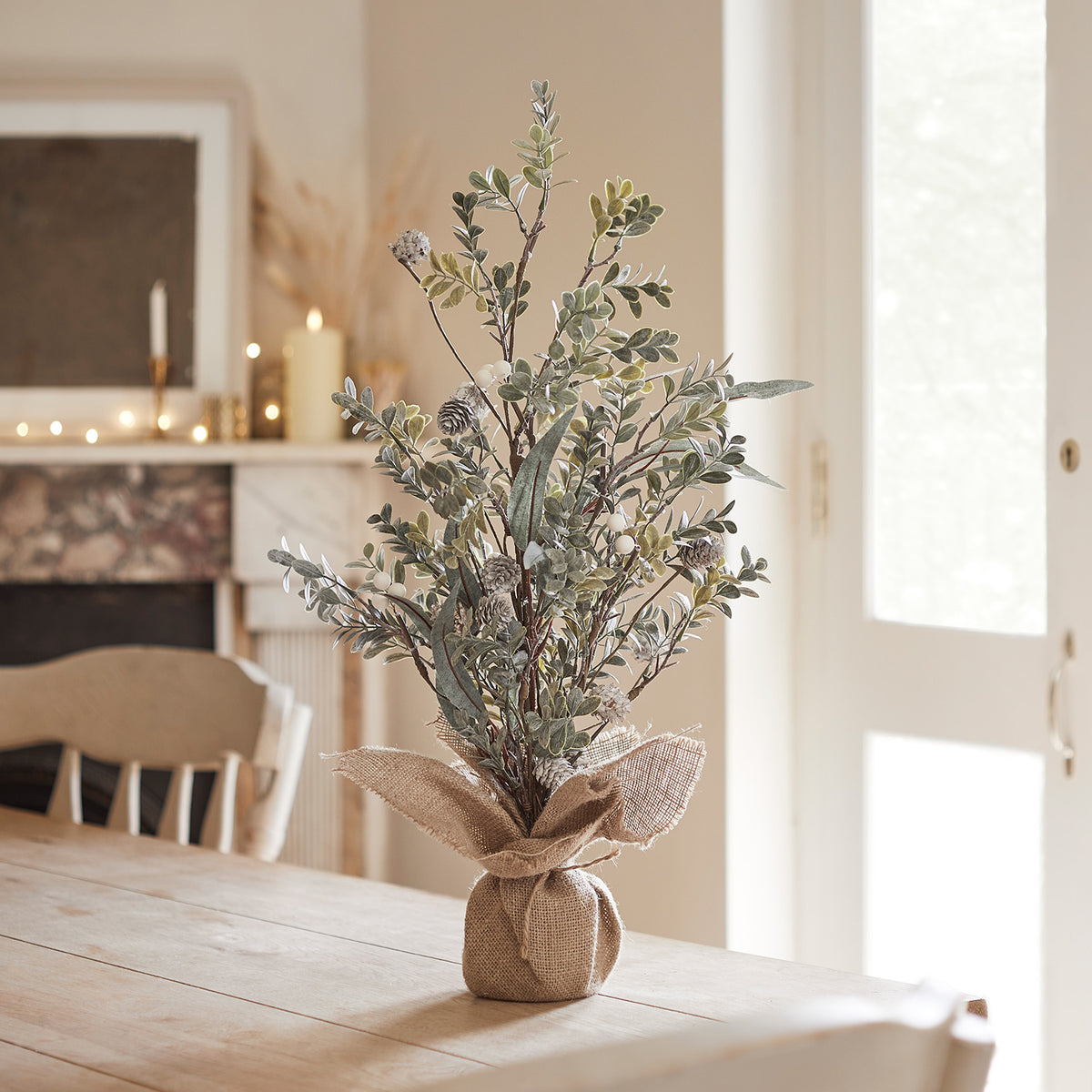 Kleiner 63cm hoher Weihnachtsbaum mit weißen Beeren und Jute umwickeltem Fuß auf Holztisch