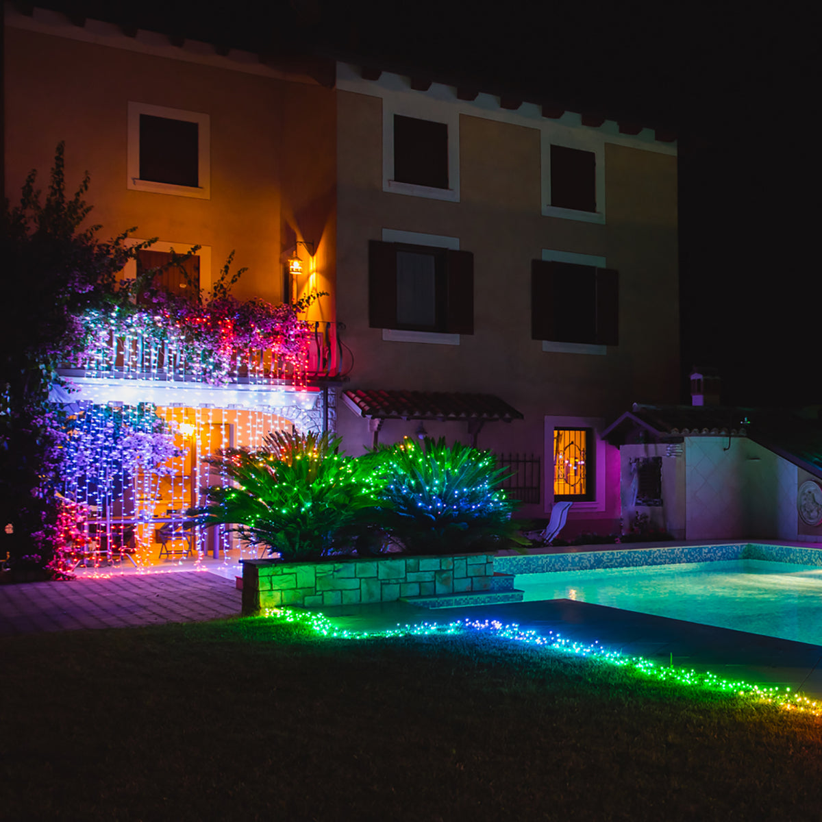 Bunte LED-Lichterkette als Lichtervorhang an einer Hecke und am Poolrand