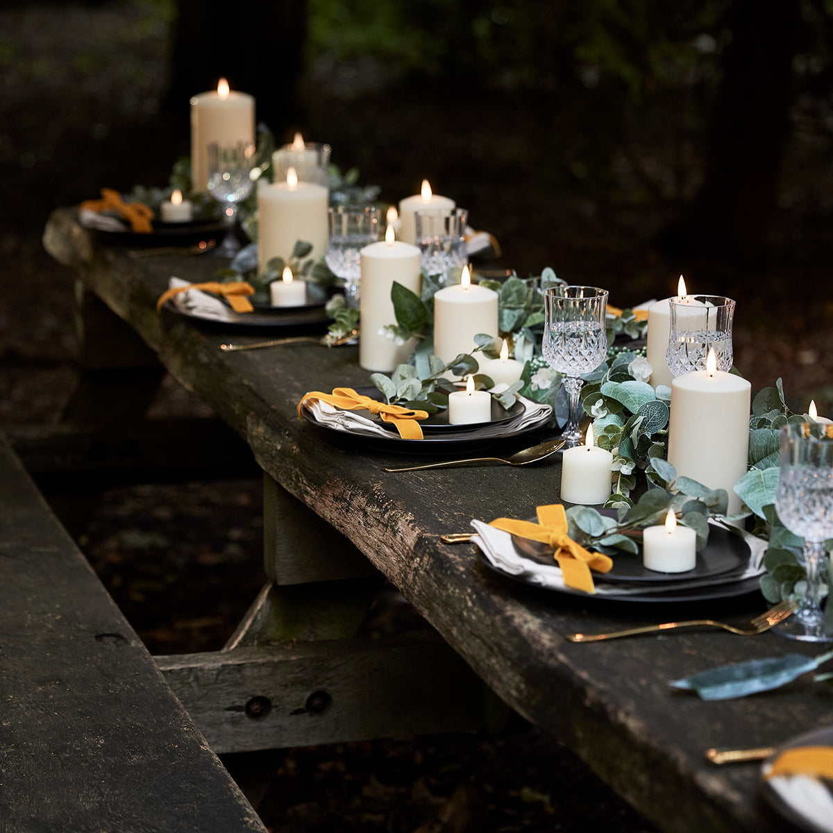 Festlich gedeckter Tisch mit brennenden LED-Kerzen, Gläsern und Dekoration im Außenbereich
