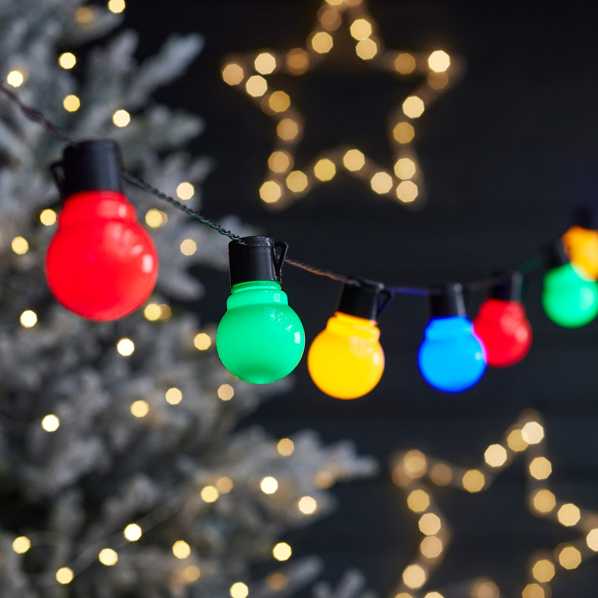 Bunte LED-Kugeln an Lichterkette mit leuchtendem Stern aus Lichtern im Hintergrund
