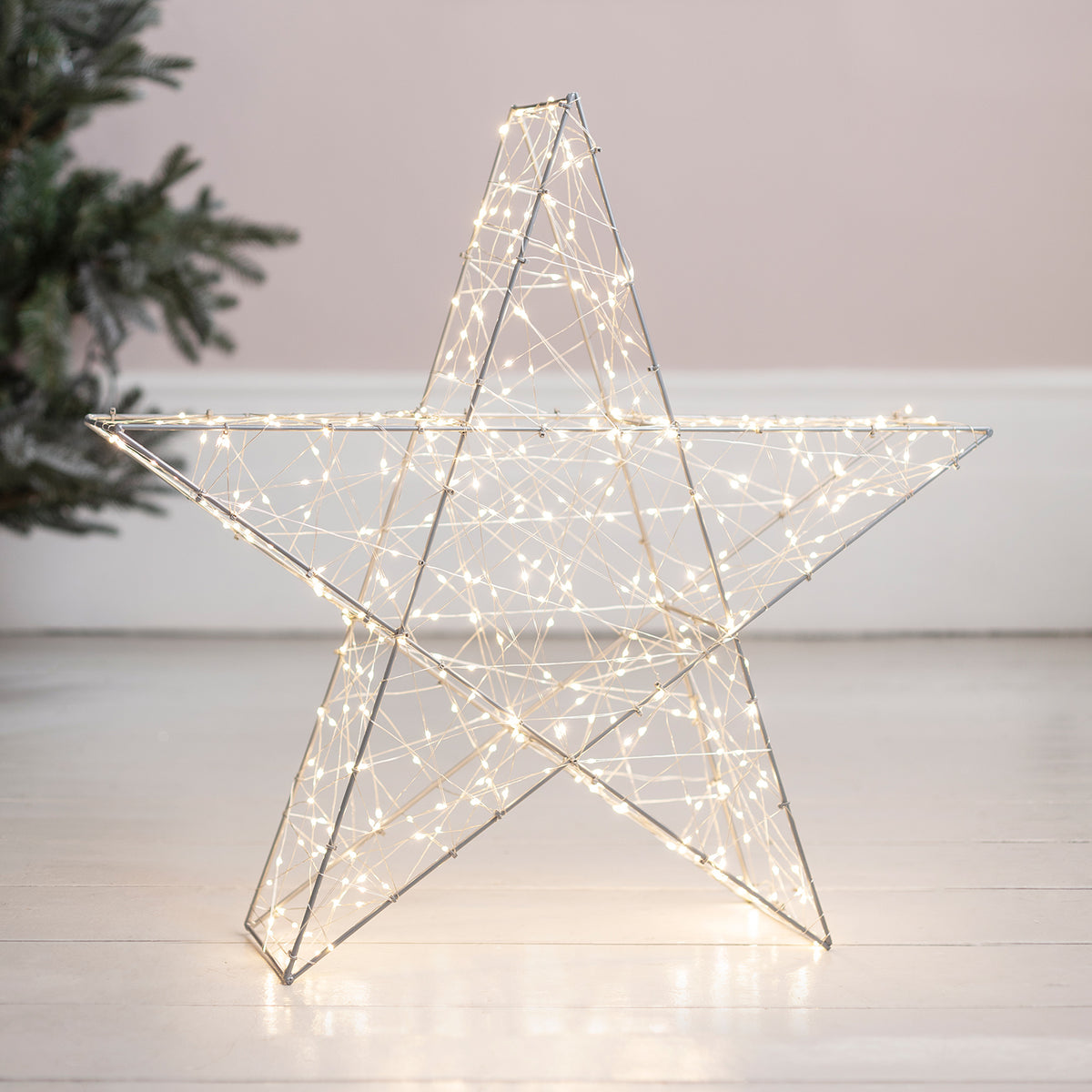 Nahaufnahme des silbernen LED Sterns mit warmweißen Lichtern auf hellem Boden