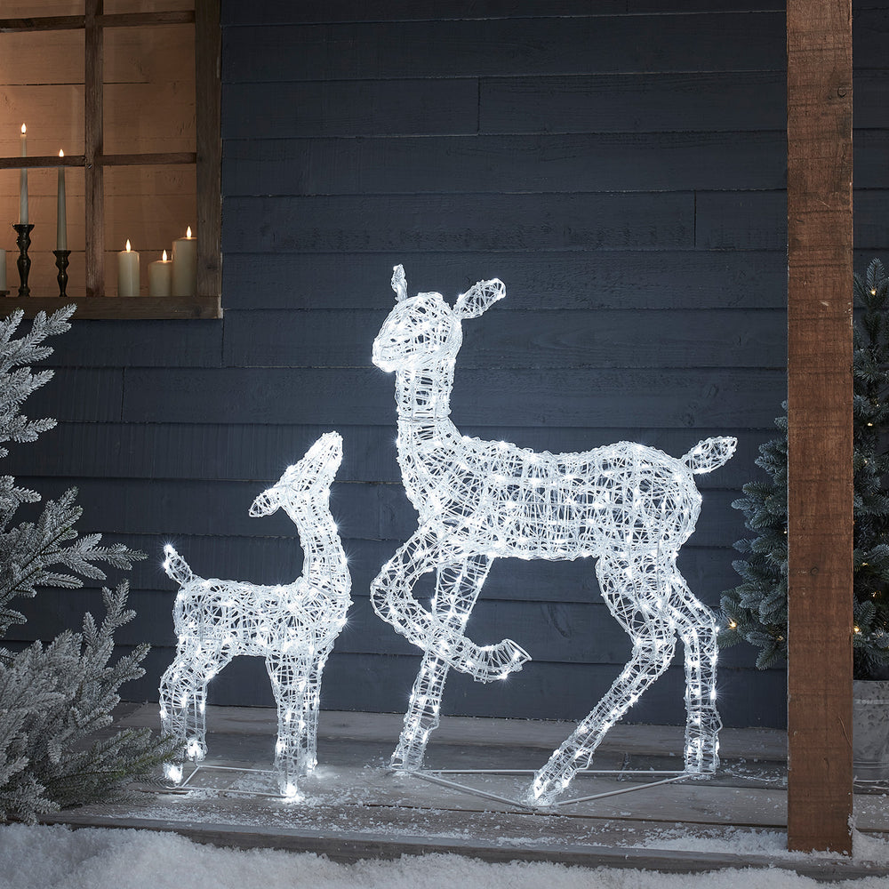 Leuchtende Acrylfiguren Rentiermutter und Rehkitz mit weißen LEDs vor dunkler Holzfassade