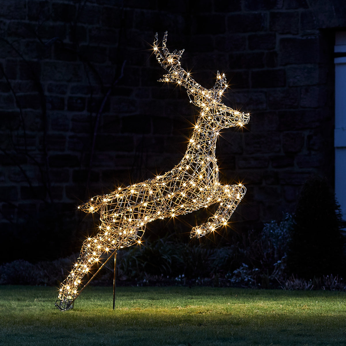Springendes LED-Rentier mit warmweißen Lichtern im Garten bei Nacht