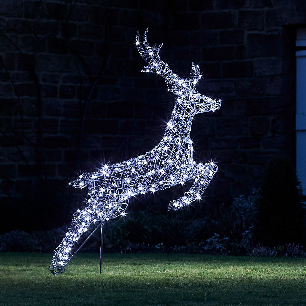 Springendes LED-Rentier mit weißen Lichtern im Garten bei Nacht