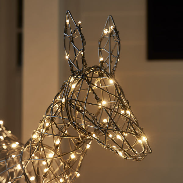 Nahaufnahme Kopf eines LED-Rentiers mit warmweißen Lichtern vor einem Haus