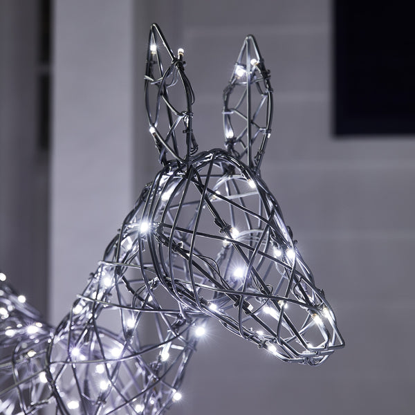 Nahaufnahme Kopf eines LED-Rentiers mit weißen Lichtern vor einem Haus