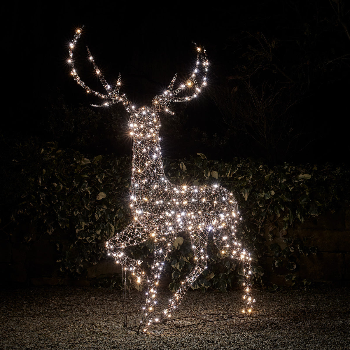 LED-Hirsch mit eisig weißen Lichtern in einem dunklen Garten