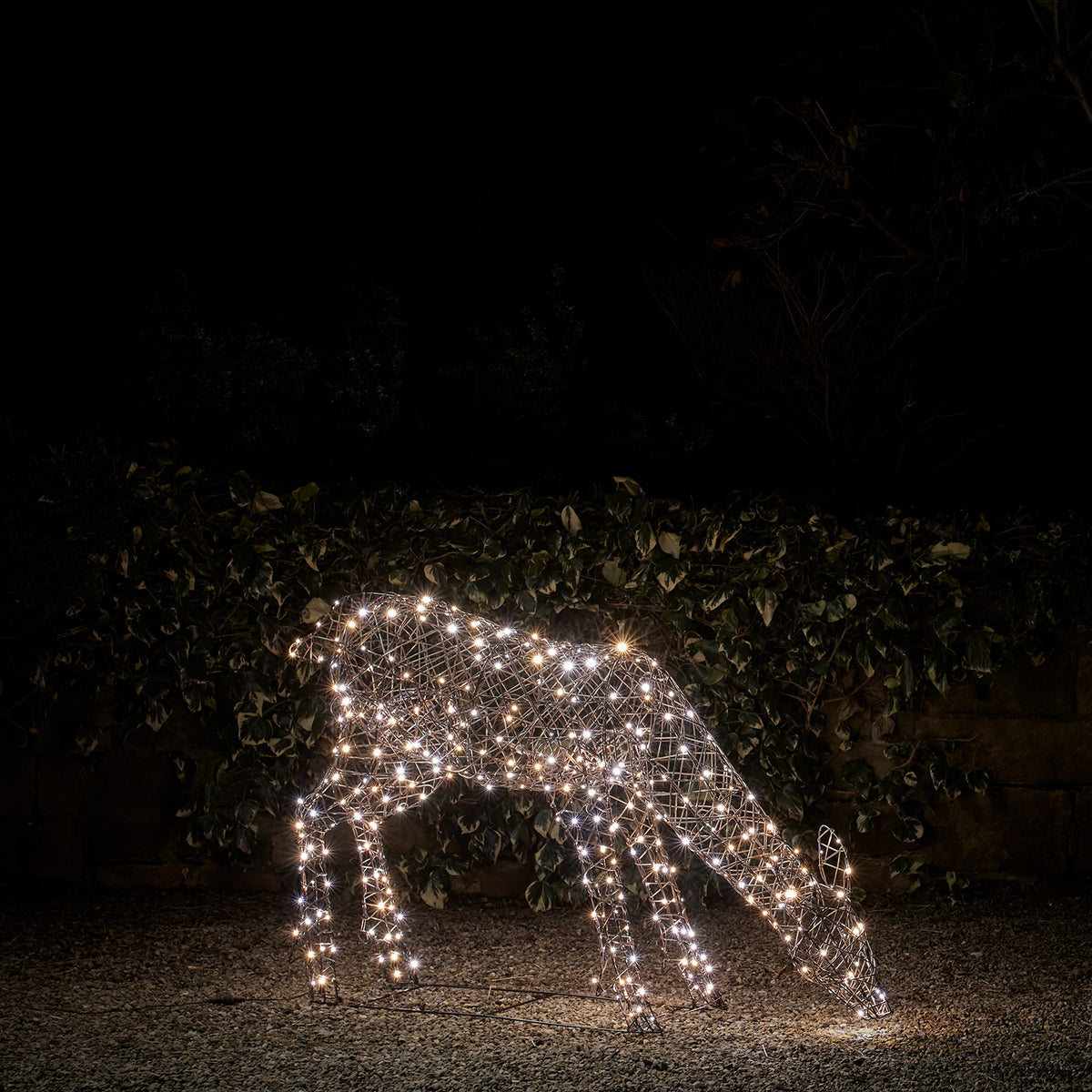 LED-Hirschkuh mit eisig weißen Lichtern in einem dunklen Garten